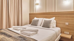 A neatly made bed with a patterned throw, a wooden headboard, and two wall-mounted light fixtures. - Superb Air-conditioned Flat on the Champs Elysees (Paris)