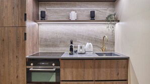 A compact kitchen with wooden cabinets, a built-in oven, a sink with a gold faucet, and a marble backsplash. - Superb Air-conditioned Flat on the Champs Elysees (Paris)