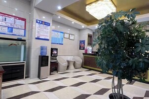 A reception area with a checkered floor, a reception desk, a water dispenser, and a large potted plant.
