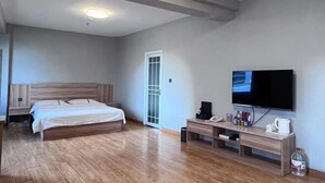 Una habitación de hotel moderna con una cama de madera, un televisor de pantalla plana, una mesita de noche y un escritorio pequeño con una silla.