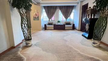 A carpeted hallway with a sofa set and a decorative cabinet.