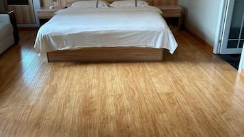A bedroom with a wooden bed, a nightstand, a chair, and a window.