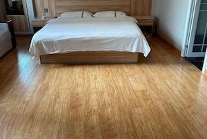 Un dormitorio con una cama de madera, una mesita de noche, una silla y una ventana.