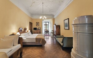 Quarto de hotel com cama, escrivaninha, cadeira, guarda-roupa e lustre.