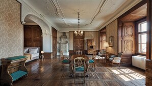 A room with a wooden floor, a dining table with chairs, a sofa, a fireplace, and a window. - Schloss Drosendorf (Drosendorf-Zissersdorf)