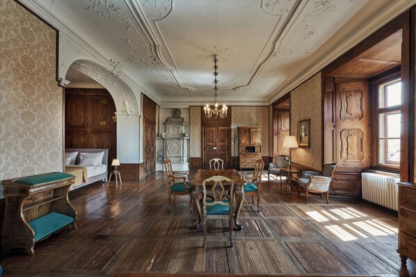 A room with a wooden floor, a dining table with chairs, a sofa, a fireplace, and a window.