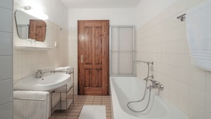 A bathroom with a sink, mirror, wooden door, shower, and a towel rack. - Schloss Drosendorf (Drosendorf-Zissersdorf)