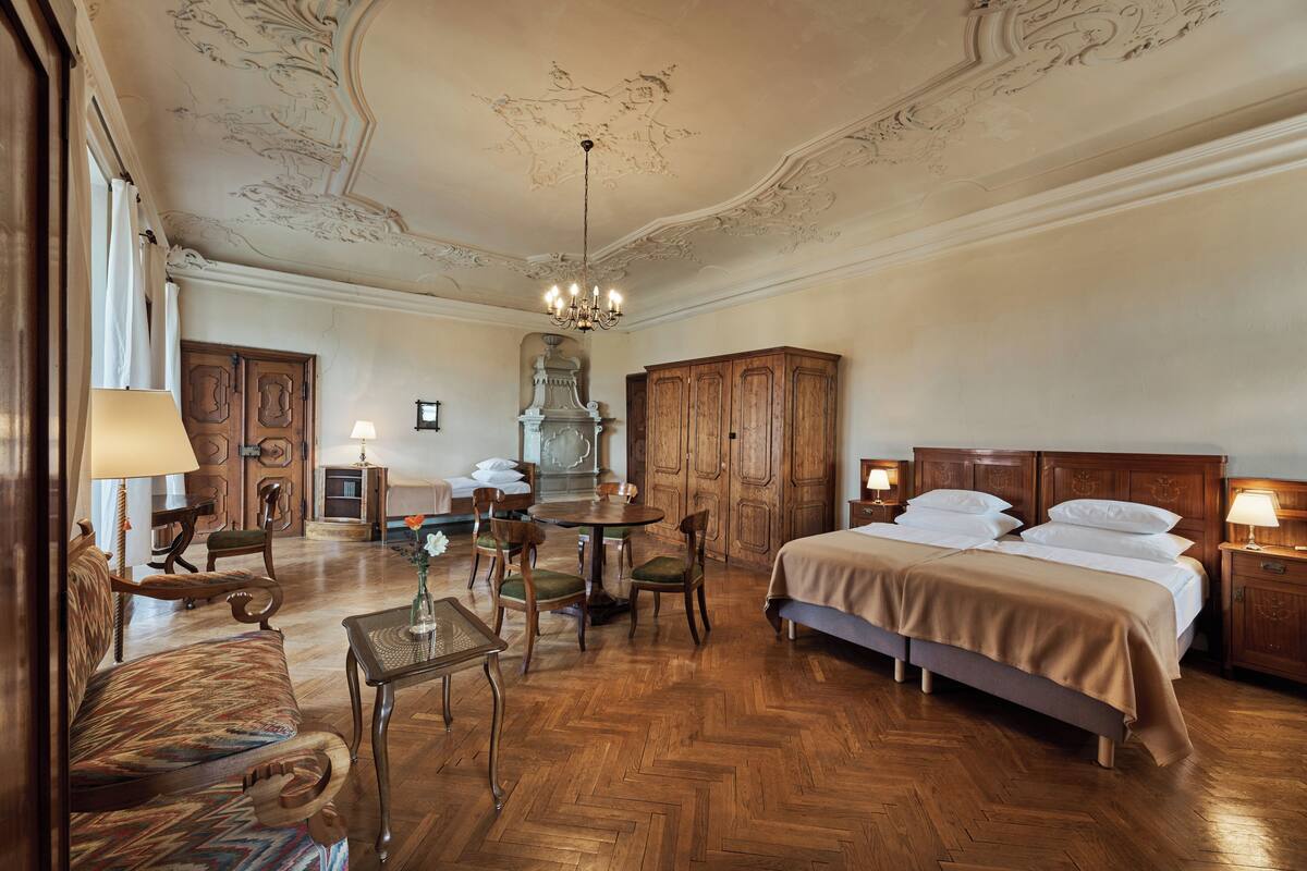 A room with a bed, wooden furniture, a chandelier, and a decorative ceiling.