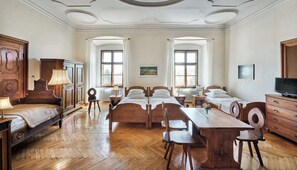 Quarto com uma cama grande, uma escrivaninha de madeira, uma televisão e um radiador.