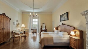 A hotel room with a large bed, wooden furniture, a chandelier, and a window with curtains. - Schloss Drosendorf (Drosendorf-Zissersdorf)