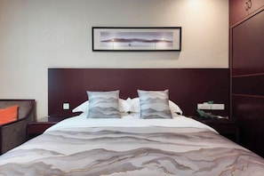 A hotel room with a bed, a nightstand, a framed picture on the wall, and a wardrobe. - Xuancheng Hotel (Xuancheng)