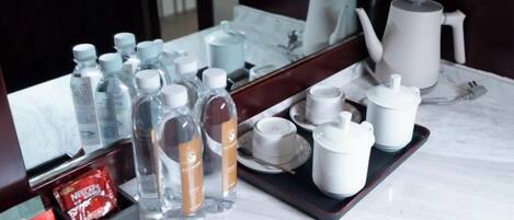 Baño de una habitación de hotel con espejo, artículos de aseo y una bandeja con tazas y tetera.