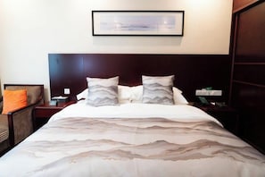 A hotel room with a large bed, two bedside tables, a nightstand, a chair, and a framed picture on the wall. - Xuancheng Hotel (Xuancheng)