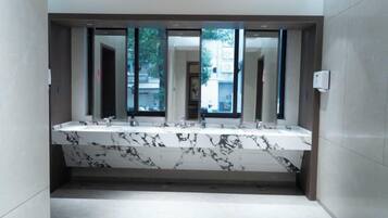 A bathroom with a marble vanity, multiple mirrors, and a view of the outside.
