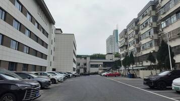 A street view with a row of parked cars, multi-story buildings, and a clear sky.