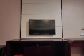 Televisão de tela plana fixada na parede acima de um armário de madeira.