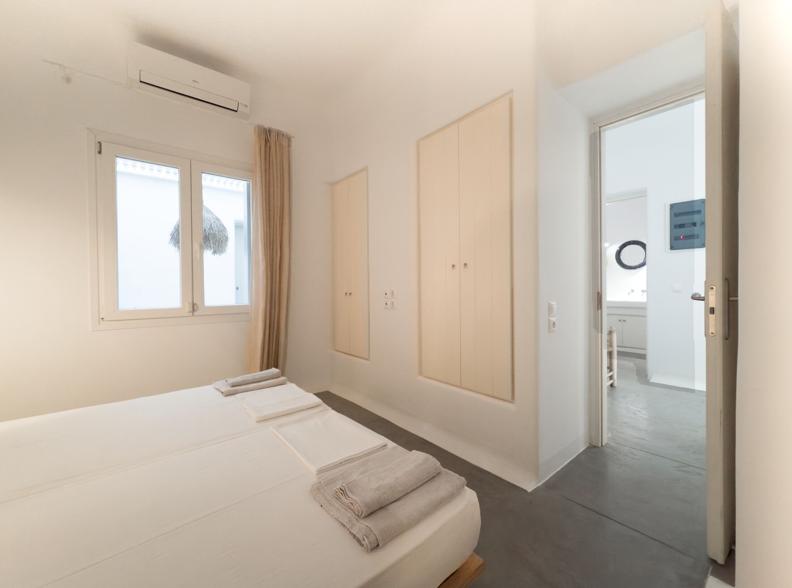 A bedroom with a large bed, a wardrobe, and a bathroom visible through an open door.