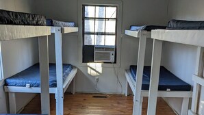 Un dormitorio con literas, una ventana y un equipo de aire acondicionado.