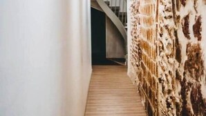 A hallway with a wooden floor, white walls, and a textured wall on the right. - The best location in the city center! (Bergerac)