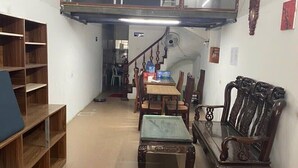 A spacious living area with a high ceiling, a dining table, chairs, a sofa, and a staircase leading to an upper level.