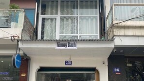 A hotel entrance with a sign reading "Nhung Bach" and a blue sign indicating room number 25B.