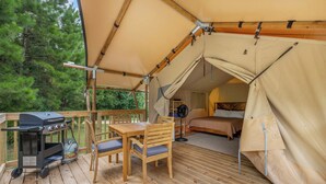 A tented accommodation with a wooden deck, a barbecue grill, and a bed inside. - Settle Into a Cozy Lakeside Glamping Escape (Onalaska)