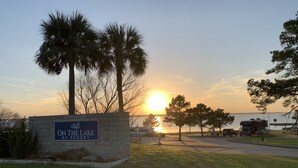 Une enseigne indiquant le nom du complexe de camping-cars « On the Lake RV Resort », avec un coucher de soleil en arrière-plan.