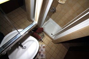 Un baño con lavamanos blanco, ducha e inodoro.
