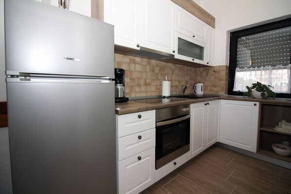 Una cocina con gabinetes blancos, un refrigerador de acero inoxidable, una cafetera y un microondas.