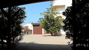 A paved courtyard with a tree and a building with a brown gate. - Zadar Coastal Haven - One Bedroom Apartment With Sea View (Zadar)