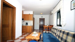 A compact living space with a checkered floor, a sofa, a dining table with chairs, and wooden cabinets. - Zadar Coastal Haven - One Bedroom Apartment With Sea View (Zadar)