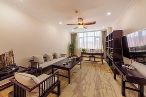 Un salon comprenant un ensemble de canapés, une table à manger, un téléviseur et un ventilateur de plafond.