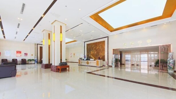 A spacious lobby with a reception desk, seating area, and a large window providing natural light. - New Shilong Hotel (Shijiazhuang)