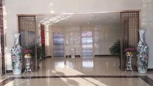 A spacious lobby with a polished floor, large vases, and a view of elevators. - New Shilong Hotel (Shijiazhuang)