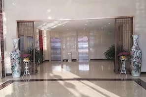 A spacious lobby with a polished floor, large vases, and a view of elevators. - New Shilong Hotel (Shijiazhuang)