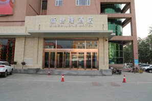 Een hotelentree met een bord waarop 'XINSHILONG HOTEL' staat.
