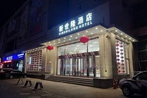 A hotel with a sign reading 'XIMSHILONG HOTEL,' large glass doors, and red lanterns. - New Shilong Hotel (Shijiazhuang)