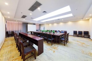 Une salle de conférence avec une longue table, des chaises, un écran de projection et un sol recouvert de moquette.