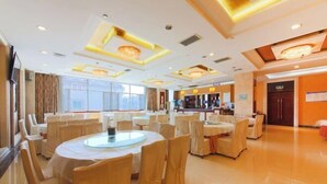 A spacious hotel lobby with round tables and chairs, a bar area, and large windows providing natural light. - New Shilong Hotel (Shijiazhuang)