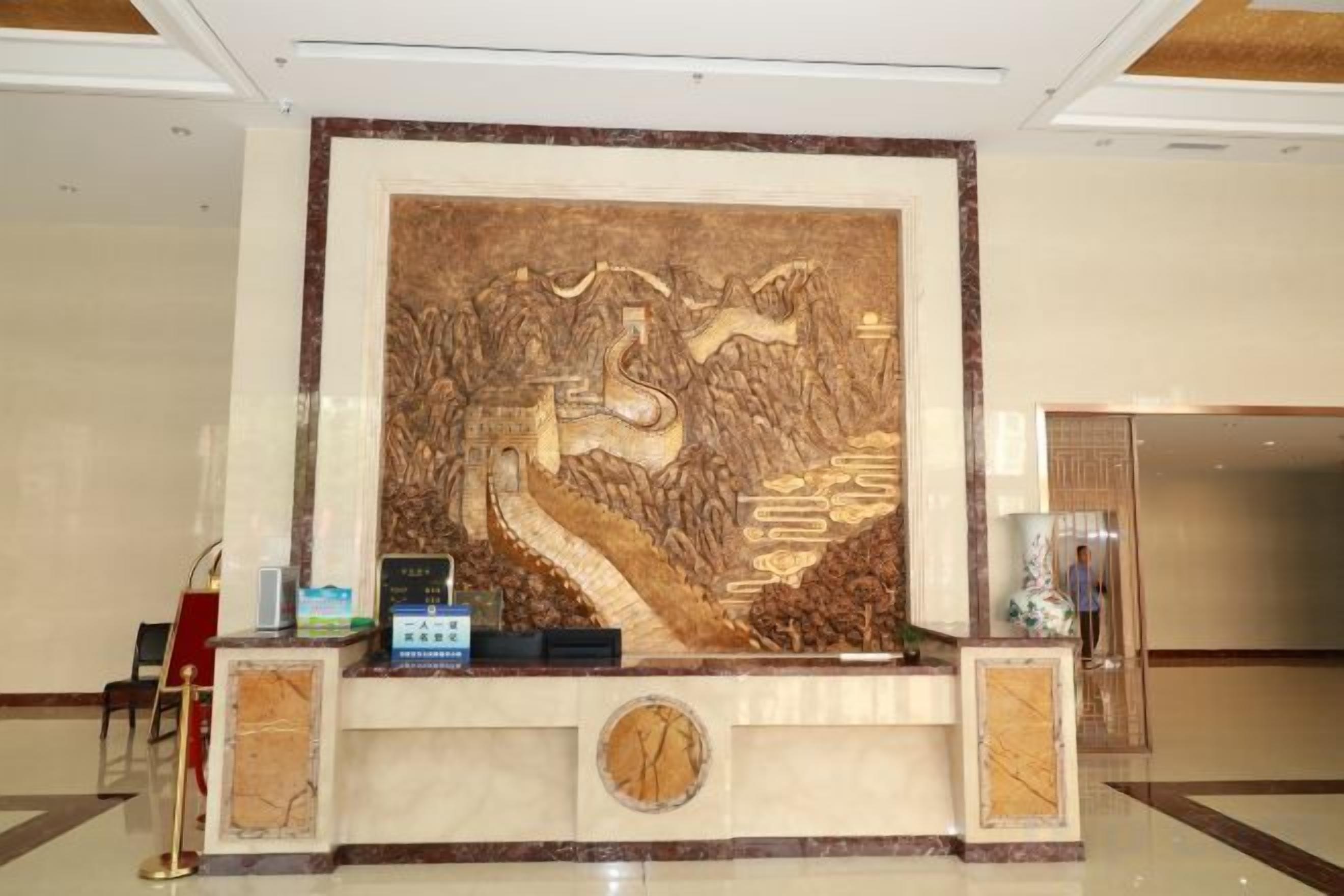A reception desk with a large decorative wall, a clock, and a small plant.