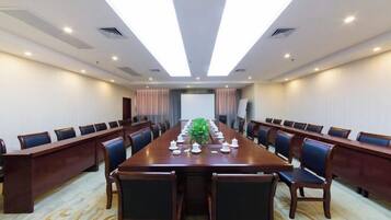 A conference room with a long table, chairs, and a projector screen.