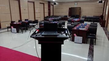 A conference room with multiple tables and chairs, a podium, and a red carpet.