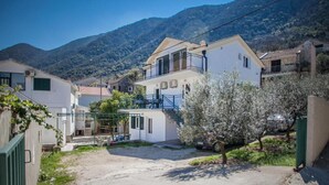 A residential area with houses, a paved courtyard, and a mountain backdrop.