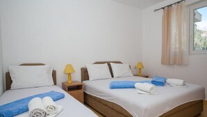 A hotel room with two beds, each with a pillow, a nightstand with a lamp, and towels on the beds.