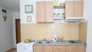 A compact kitchen with wooden cabinets, a sink, a white refrigerator, and a tiled backsplash.