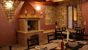 Un comedor con chimenea de piedra, vigas de madera y pared de piedra.