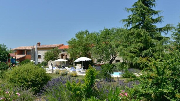 Una villa con piscina, rodeada de exuberantes jardines y un cielo azul cristalino.