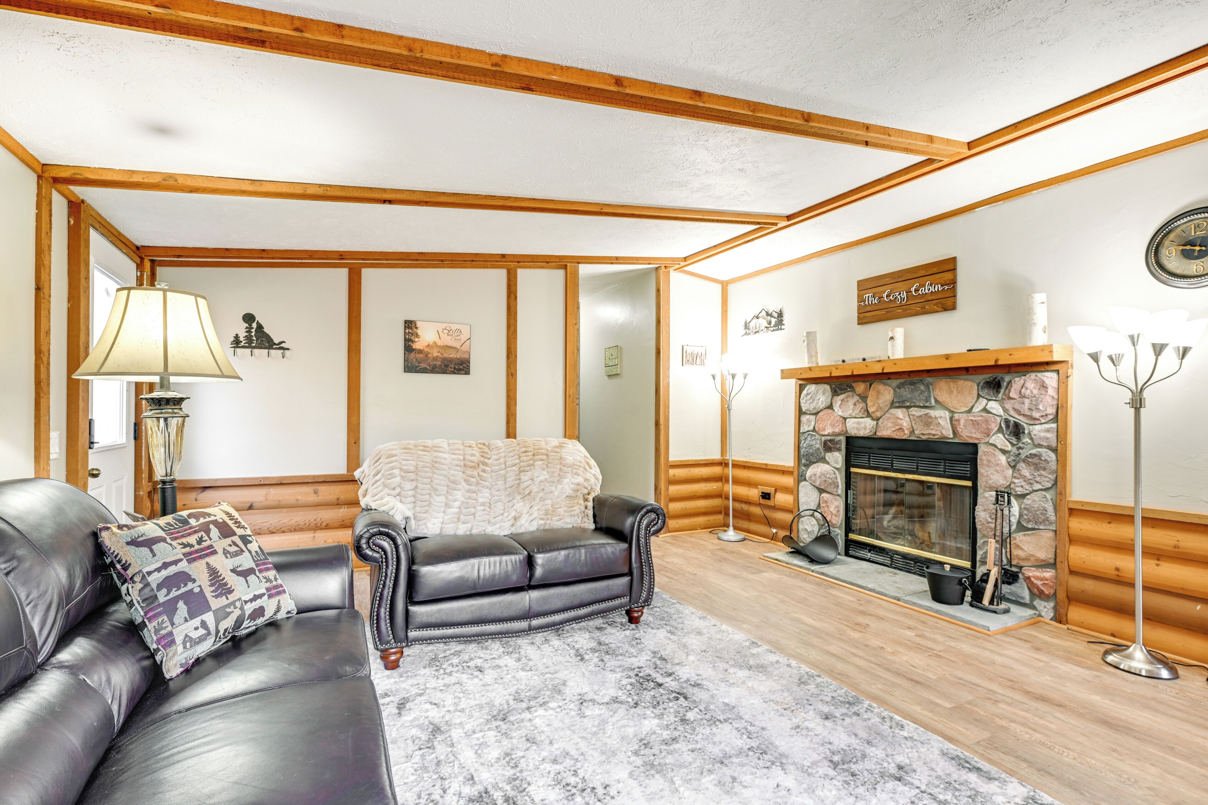 A cozy living room with a fireplace, a leather sofa, and a stone fireplace surround.