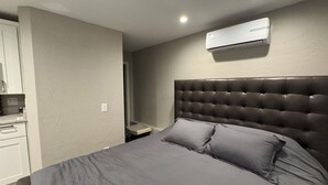 Un dormitorio con una cama grande, cabecera y un equipo de aire acondicionado en la pared.
