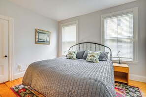 A bedroom with a bed, a nightstand, a lamp, and a window with blinds. - Walk to Harvard Square: Apartment in Cambridge (Cambridge)